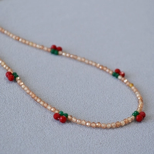 Macro shot of handmade beaded necklace with champagne crystals and cute red cherry charms