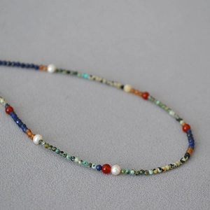 Macro shot of minimalist lapis and turquoise beaded necklace with freshwater pearls