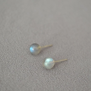 Close-up of minimalist labradorite stud earrings with blue flash and gold needles