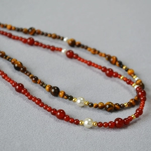 Close-up of vintage beaded necklace with red agate, tiger eye stones and white pearls