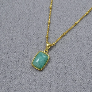 Detail of green rectangular natural stone pendant on 18K gold plated beaded chain necklace