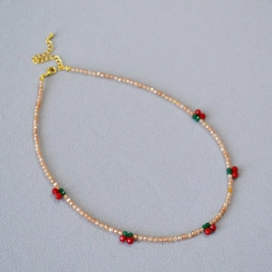 Elegant champagne beaded necklace featuring cute red cherry accents and a gold lobster clasp