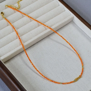 Vue détaillée du collier de perles orange avec pendentif poisson koi doré sur plateau