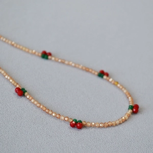 Detail of beaded necklace with champagne crystals and cute red cherry charm accents