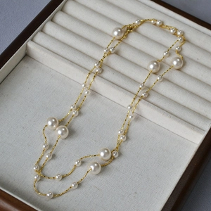 Collier élégant en chaîne dorée avec plusieurs perles blanches sur un plateau en velours