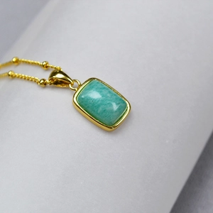 Macro detail of rectangle green natural stone pendant with gold plated beaded chain necklace