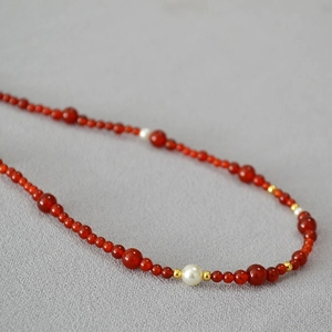 Macro detail of red agate beads and white pearls on a vintage beaded necklace chain