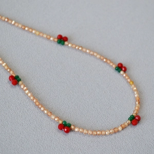 Detailed macro view of champagne beaded necklace featuring cute red cherry charms