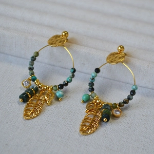 Close-up of bohemian gold hoop earrings featuring turquoise beads and leaf pendants