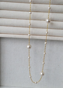 Gros plan détaillé des perles blanches sur une élégante chaîne de collier long doré