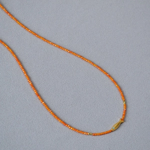 Vue détaillée du collier de perles orange avec un pendentif carpe koi dorée et du zircon