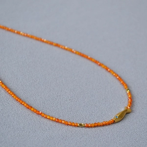 Collier minimaliste en perles oranges avec pendentif carpe koi dorée serti d'une pierre bleue