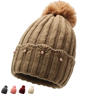 Close-up of pearl bead accents on knit beanie with large faux fur pom-pom detail