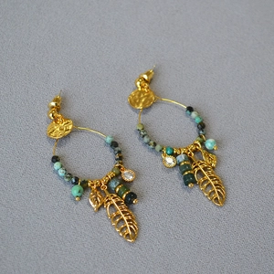 Close-up of bohemian gold feather earrings with turquoise beads and crystal accents