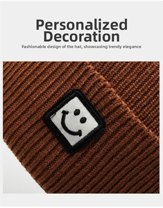 Close-up detail of knitted beanie featuring a square smiley face embroidery patch