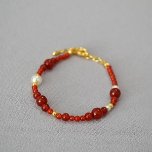 Detail of red agate and tiger eye beaded necklace with pearls and gold accents
