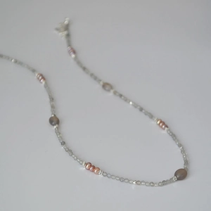 Detailed shot of handmade labradorite beads and freshwater pearl necklace on white base