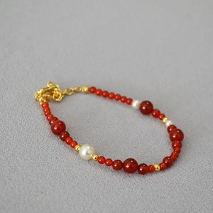 Macro shot of red agate and freshwater pearl necklace with adjustable gold lobster clasp