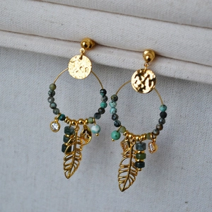 Detailed close-up of Bohemian gold earrings featuring turquoise beads and feather charms