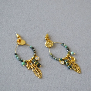 Detail of bohemian gold hoop earring with turquoise beads and leaf feather pendant