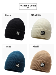Detail view of knitted beanies in black, white, blue and khaki with smiley face patches