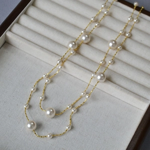 Détail d'un long collier de perles élégant avec chaîne dorée sur un plateau en velours