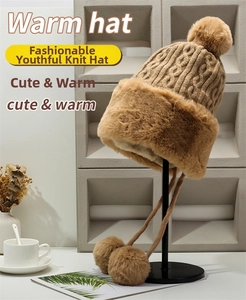 Detail of cable knit trapper hat with faux fur trim and decorative hanging pom-poms