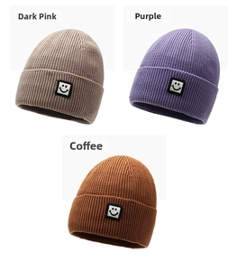 Detail view of multi-color ribbed knit beanies with smiling face patches in various colors