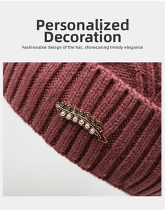 Detail of dark red knit beanie showing vertical ribbed pattern and gold feather brooch