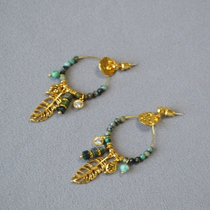 Detail of bohemian gold hoop earrings with turquoise beads and hollow feather charms