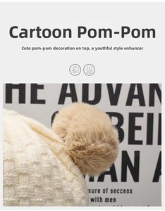 Dettaglio di un cappello in maglia a nido d'ape beige con un grande pompon di pelliccia
