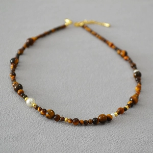 Detail of beaded necklace with tiger eye stones, pearls, and golden metal spacers