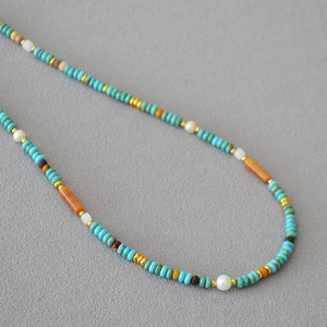 Detailaufnahme der Boho-Halskette mit Türkis, Goldperlen, Perlen und orangen Steinen