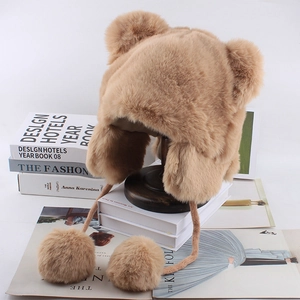 Close-up of plush bear ear trapper hat with soft faux fur texture and large pom-poms