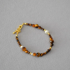 Macro detail of handmade tiger eye beads and pearl necklace with golden clasp