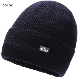 Close-up of a dark blue ribbed knit beanie featuring a mountain logo patch on the cuff