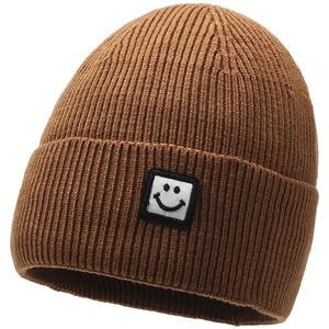 Detail shot of caramel brown knitted beanie with minimalist black smiley face patch logo