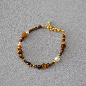 Detail of red agate and tiger eye beads necklace with gold lobster clasp and chain