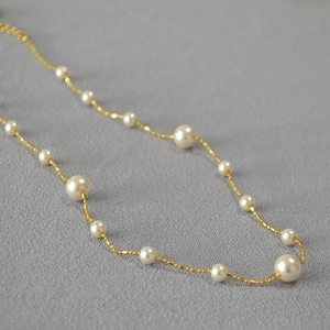 Gros plan détaillé de perles rondes brillantes sur un collier long à chaîne perlée dorée