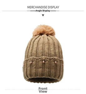 Detail of khaki knit beanie with fluffy pompom and elegant pearl embellishments