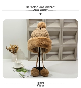 Detailed knit texture of a warm winter earflap hat with large decorative faux fur pom poms