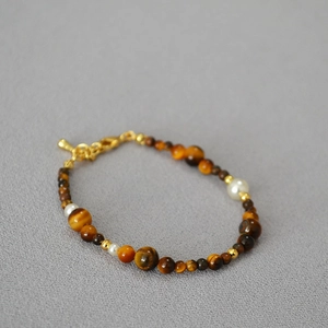 Detailed view of beaded necklace with tiger eye stones, pearls, and golden lobster clasp