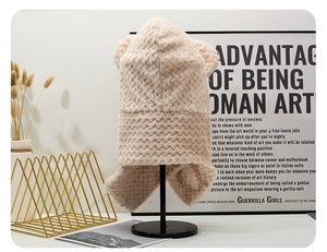 Detail of plush off-white bear ear hat with thick faux fur wave knit texture on a stand
