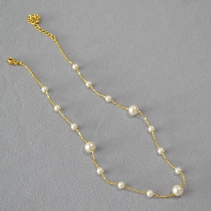 Détail d'un collier de perles doré élégant avec plusieurs perles et fermoir mousqueton