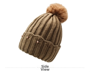 Detail of winter knit beanie showing pearl embellishments and fluffy faux fur pom-pom