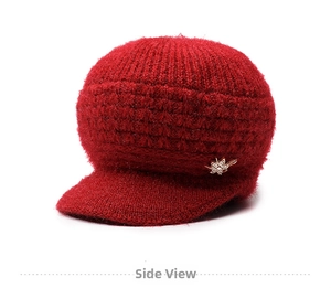 Dettaglio del cappello invernale in maglia rosso scuro per anziane con spilla a fiore
