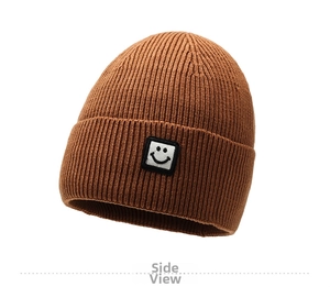 Close-up of caramel ribbed knit beanie with small smiley face patch on folded brim