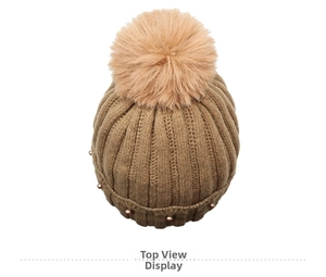 Top down view of brown knit beanie featuring large faux fur pompom and pearl bead accents
