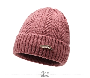 Detail of pink knitted winter hat featuring golden leaf ornament with white pearls