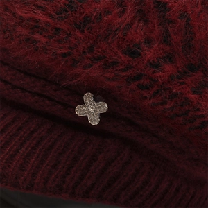 Detail of burgundy knitted hat with plush texture and silver clover rhinestone accent
